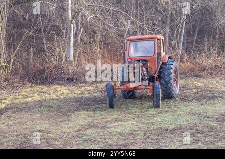 Tractor. Old rusty red antique tractor from a farm in the woods. Stock Photo