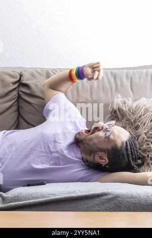 Lazy young man lying on sofa sleepy. Relaxed man lying on the sofa in the apartment. Lazy man lying on a sofa Stock Photo