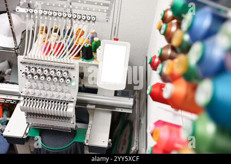 Modern embroidery machine with spools of thread indoors Stock Photo