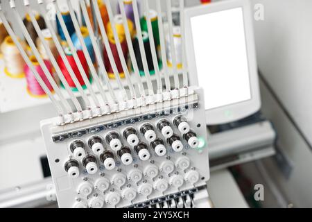Modern embroidery machine with spools of thread indoors, selective focus Stock Photo