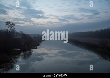 Fisherman boat in river on an early foggy morning at dawn. Dramatic landscapes. Stock Photo