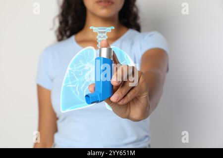 Woman holding asthma inhaler on white background, closeup. Illustration of lungs Stock Photo