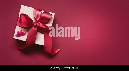 White paper box with ribbon isolated on red background, valentines day, copy space for text. Stock Photo