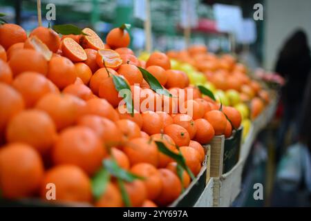 Fresh mandarin oranges or tangerines fruit with leaves in boxes at the open air local food market. Wholesale depot of exotic fruits. Local produce at Stock Photo