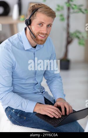 young businessman using laptop and wearing headset Stock Photo