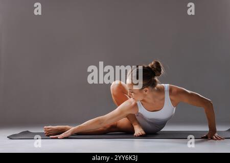 woman in white sportswear practicing complex yoga poses, stretching and pilates training, Stock Photo