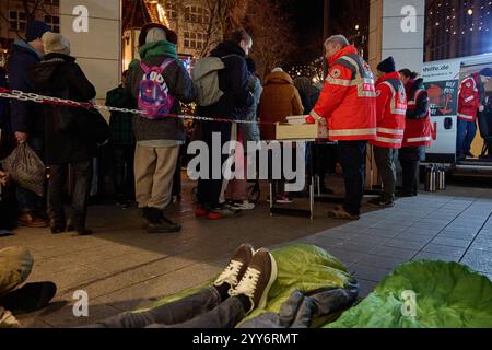 Hamburg, Germany. 19th Dec, 2024. Volunteer members of the German Red Cross (DRK) distribute food to homeless people at Gerhart-Hauptmann-Platz. Credit: Georg Wendt/dpa/Alamy Live News Stock Photo