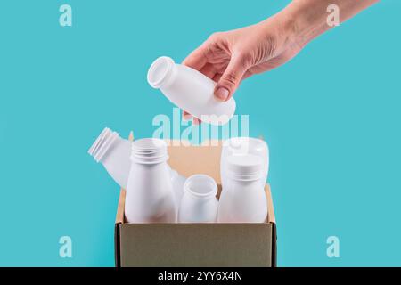 Womans hand drops white plastic bottle into container Stock Photo