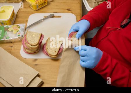 Hamburg, Germany. 19th Dec, 2024. A volunteer member of the German Red Cross (DRK) packs loaves of bread that will later be distributed to people in need in the city center. Credit: Georg Wendt/dpa/Alamy Live News Stock Photo