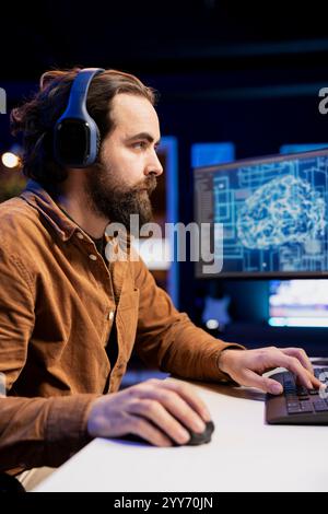 Freelancing developer listening audiobooks, building artificial intelligence neural networks computerized models. Tech support specialist enjoying podcasts while doing checkup on AI systems Stock Photo