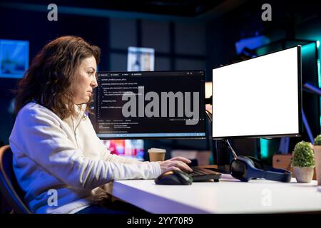Programmer doing software debugging on isolated screen PC at home, checking broken lines of code displayed on monitors. Woman in living room fixing coding problems on mockup computer Stock Photo