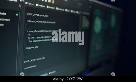 Desk with decorations in empty criminals den and hacking software interface on PC screens. Equipment in apartment used for deploying malware programming script on displays in underground base Stock Photo