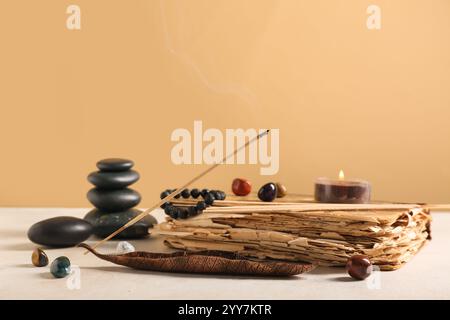 Composition with aromatic incense sticks, old book and spa stones on light table against color wall Stock Photo