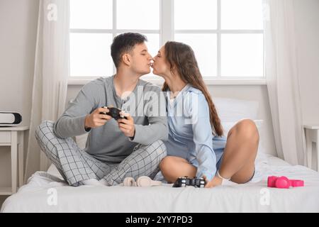 Young couple kissing while playing video game in bedroom Stock Photo
