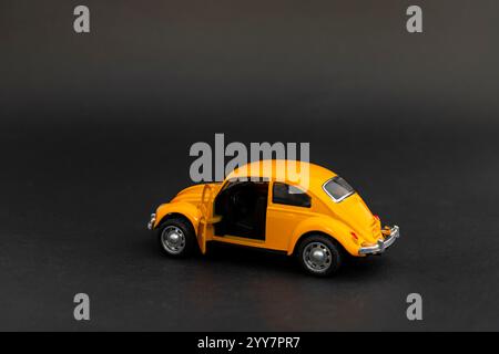Yellow metal toy car model with open door on black background Stock Photo