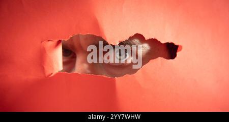 Man looking through hole in paper. Stock Photo
