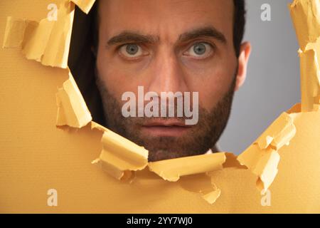 Man looking through hole in paper. Stock Photo