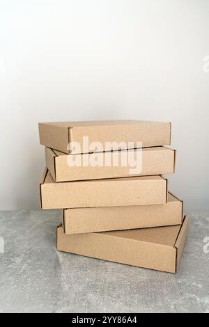 A stack of self-assembly kraft cardboard boxes arranged on a textured surface. Ideal for packaging, gift wrapping, and shipping. A sustainable choice Stock Photo