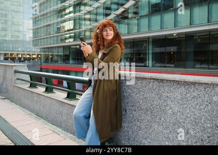 Woman listening to music with headphones and using phone in the city Stock Photo