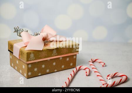 Festive gold gift with pink ribbon, glitter decor, and candy can Stock Photo