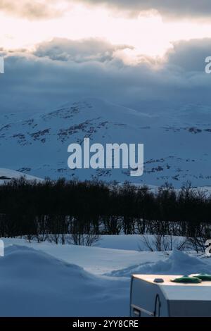 Sunlight Breaking Through Clouds Over Snowy Nordic Landscape and Stock Photo