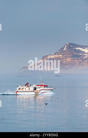 Boat cruising on icy waters near mountain Stock Photo