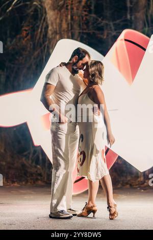 Couple embracing in front of glowing white and red abstract light art Stock Photo