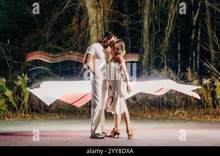Couple sharing a romantic embrace with light trails glowing behind Stock Photo