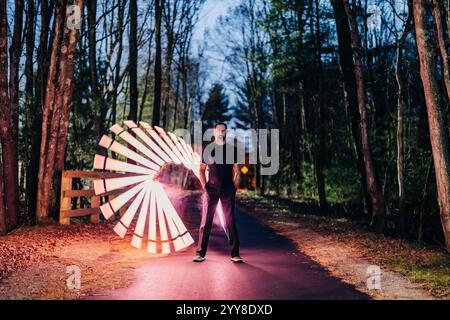 Man standing in forest with a glowing spiral-shaped light design Stock Photo