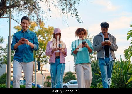 Friends walking and using smartphones during a sunny day in the park Stock Photo