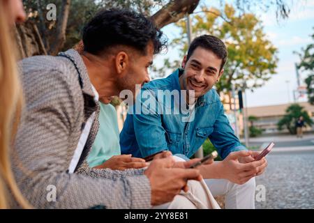 Friends enjoying time together while using smartphones in a park Stock Photo