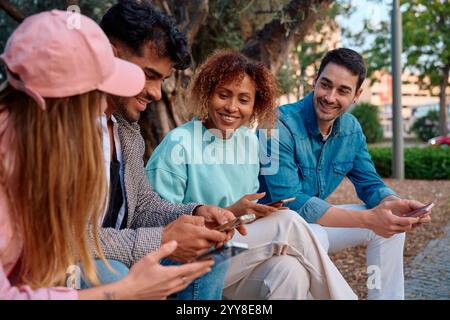 Friends enjoying time together while using mobile devices in a park Stock Photo