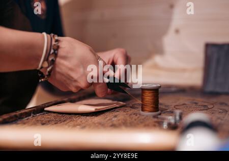 Leather artisan cutting thread for sewing handmade leather goods Stock Photo
