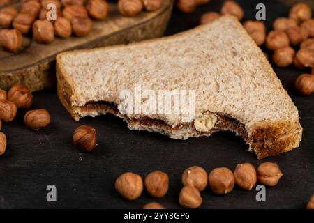 hazelnuts and bread with nut paste with chocolate closeup, delicious and sweet chocolate butter with nuts on the black slate Stock Photo