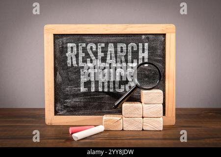 Research ethics. Miniature chalkboard and magnifying glass on a wooden table. Stock Photo