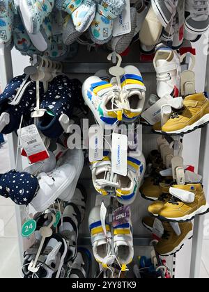 Kyiv, Ukraine - December 18, 2024: Vibrant collection of children's footwear in various sizes and designs, organized on shelves within a shop. Include Stock Photo