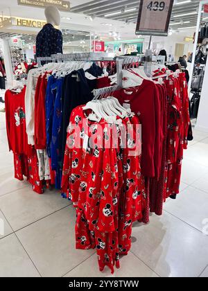 Kyiv, Ukraine - December 18, 2024: Festive clothing featuring holiday-themed patterns is neatly displayed on racks in a brightly lit store. Seasonal d Stock Photo