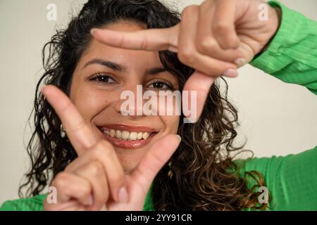Portrait of a cheerful young woman framing her face with her fingers Stock Photo