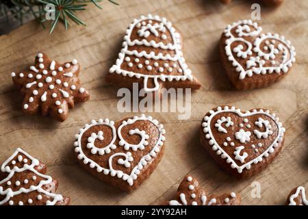 Heart, star and bell shaped homemade gingerbread Christmas cookies decorated with white icing on a wooden table Stock Photo