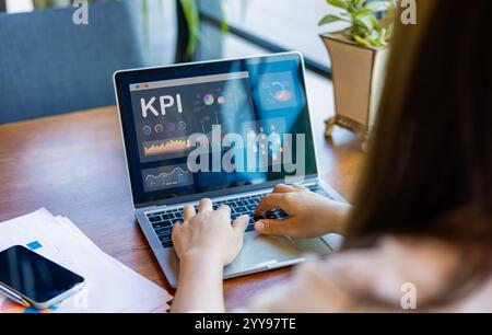 Businesswoman analyst utilizes a computer and a dashboard for business data analysis and a data management system with KPI. The concepts of technology Stock Photo