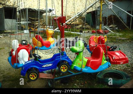 An abandoned and unmaintained kiddie carousel ride in a park that has been left behind Stock Photo