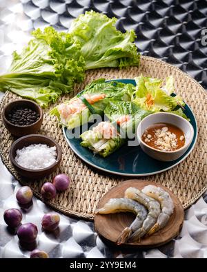 A delicious Vietnamese appetizer duo: crispy fried fish cakes and fresh shrimp spring rolls, served with vibrant salad greens for a refreshing crunch. Stock Photo
