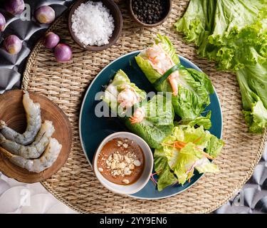 A delicious Vietnamese appetizer duo: crispy fried fish cakes and fresh shrimp spring rolls, served with vibrant salad greens for a refreshing crunch. Stock Photo