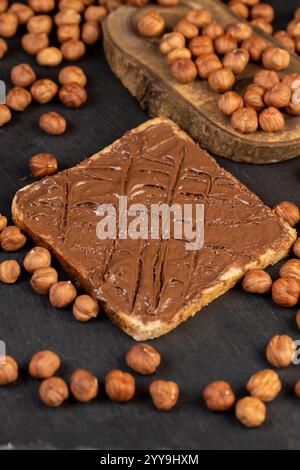 hazelnuts and bread with nut paste with chocolate, delicious and sweet chocolate butter with nuts on the table closeup Stock Photo