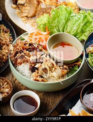 A traditional Vietnamese vermicelli bowl (Bún Thịt Nướng) with grilled pork, crispy spring rolls, fresh vegetables, pickled carrots and daikon Stock Photo