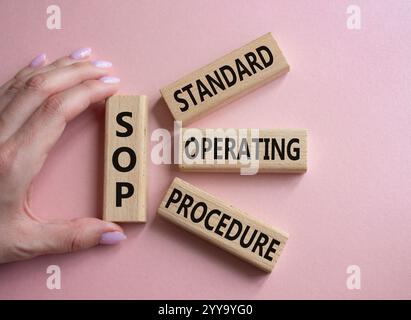 SOP - Standard Operating Procedure symbol. Wooden blocks with word SOP. Businessman hand. Beautiful pink background. Business and SOP concept. Copy sp Stock Photo