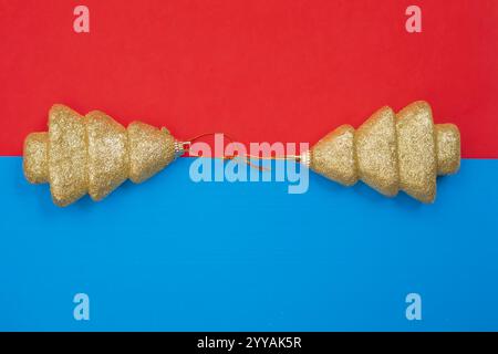 Elegant golden glitter Christmas tree decorations displayed on a blue and red split background. Perfect for holiday themes, festive celebrations, and Stock Photo