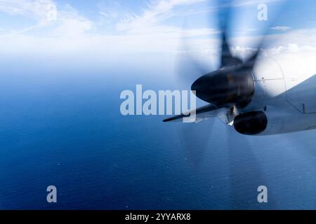 Wingview Propeller Plane Flying Over the Atlantic Ocean With Vibrant Blue Sky and Clouds Stock Photo
