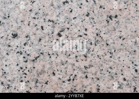 A stone wall with a lot of small holes. The holes are black and white. The wall is gray Stock Photo