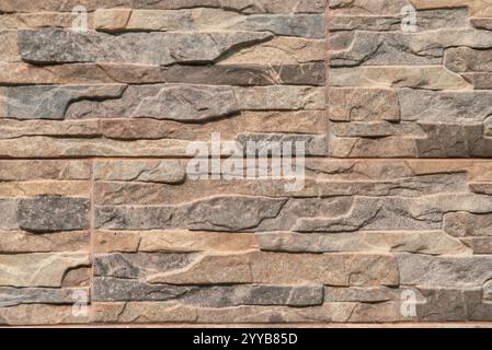 The wall is made of stone and has a brown and gray color. It is a very rough and textured surface, with many different shapes and sizes of stones. The Stock Photo